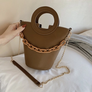 Brown bucket bag for women with round handle and acrylic chain strap in a casual lifestyle setting