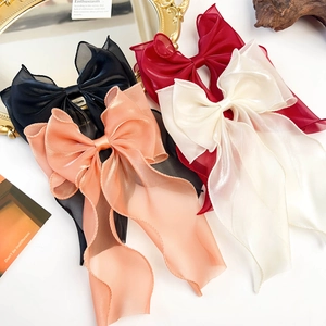 Detail of four organza bow hair clips in black, wine red, champagne, and cream colors