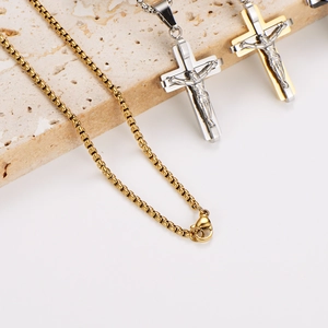 Three minimalist stainless steel cross necklaces in silver and gold on a stone base