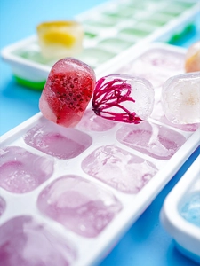 Close-up of 14-grid silicone ice cube tray with fresh strawberry and petal infused cubes