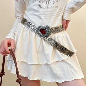 Detail of vintage metal belt featuring a large heart buckle and red gemstone inlay