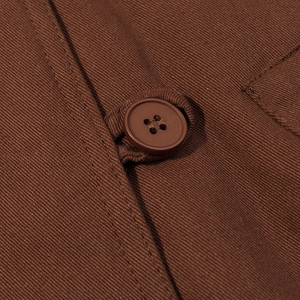 Primer plano de chaqueta corta vintage marrón con costuras detalladas y botón de cuatro agujeros