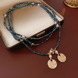 Close-up of vintage multi-layer beaded necklace with gold bee and coin pendants
