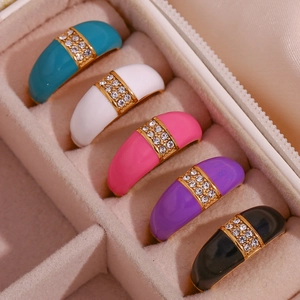 Macro shot of colorful enamel rings with inset rhinestones in a beige jewelry box