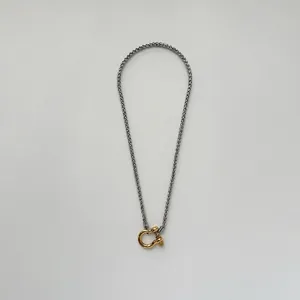 Detail of a two-tone stainless steel wheat chain with a gold-plated shackle clasp