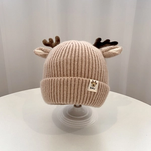 Close-up of knit baby hat with reindeer antlers on a minimalist display stand