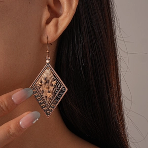 Detailed close-up of retro ethnic hollow rhombus earrings with beige tassels on model
