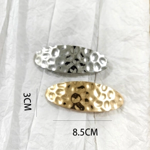 Detailed view of 8.5cm brushed metal hair clips in gold and silver with hammered finish