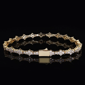 Close-up of golden tennis bracelet featuring cross links and pavé set white zircons