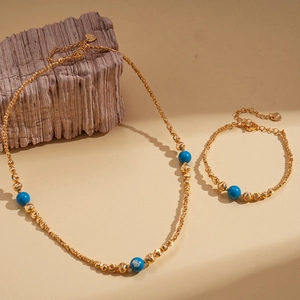 18K gold plated necklace and bracelet set with sky blue stone beads on stone background
