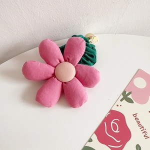 Detailed view of a pink fabric flower hair scrunchie with a green pleated band