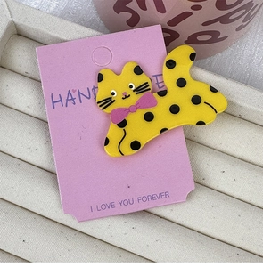 Detailed macro view of yellow polka dot cat hair clip with pink bow on purple card