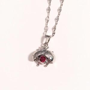 Detailed close-up of a silver ladybug pendant with a red gemstone and sparkling accents