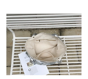 Interior view of silver nylon tote bag showing beige lining and zipper pocket details