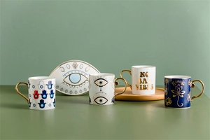Detail of ceramic mugs with gold handles featuring Hamsa Hand and Namaste symbols