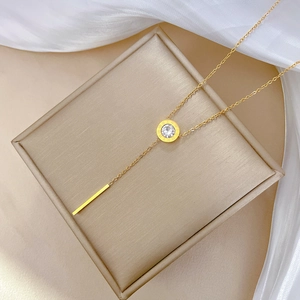 Close-up of gold titanium Roman numeral pendant and long tassel on Y-shaped necklace