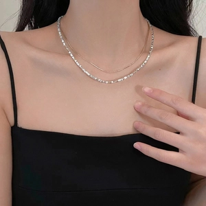 Close-up of layered silver geometric choker and thin gold necklace on a model's neck