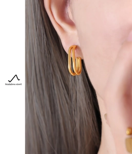 Close-up of modern double hoop stainless steel earrings in gold finish on a model