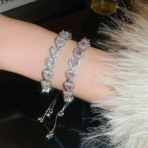 Close-up of stacked heart-shaped bracelets with pink zircon and adjustable slide clasp
