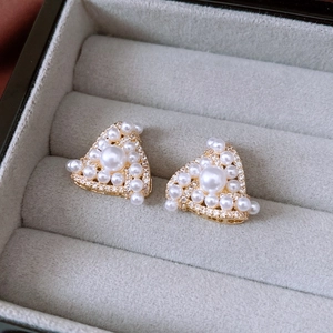 Macro shot of gold plated triangle stud earrings with pearls and cubic zirconia