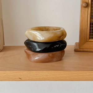 Three-piece set of resin bangles with marble texture in cream, black, and brown amber colors