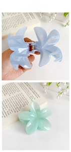 Macro view of pastel Frangipani flower hair claws in light blue and green resin finish