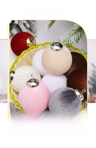 Close-up of assorted velvet Christmas balls in a woven basket with festive cedar branches