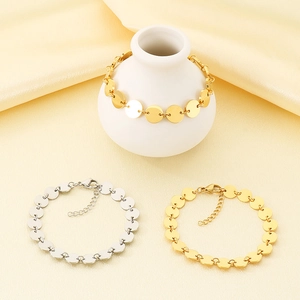 Close-up of polished gold and silver disc chain bracelets with lobster clasp detail