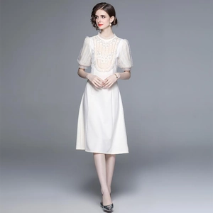 Robe blanche mi-longue élégante avec manches bouffantes et broderie sur un mannequin