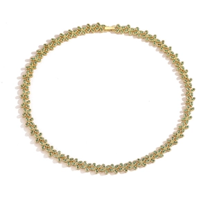 Detailed view of leaf-shaped gold necklace set with green crystals on white background