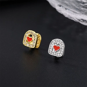 Detail of gold and silver heart grillz featuring white zircon and red enamel finish