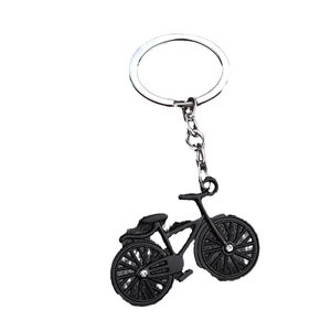 Black bicycle shaped keychain with sparkling rhinestones on minimalist white background