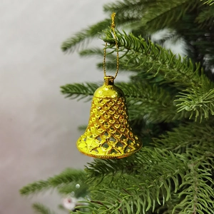 Detailansicht einer goldenen hohlen Weihnachtsklocke, die an einem Tannenzweig hängt