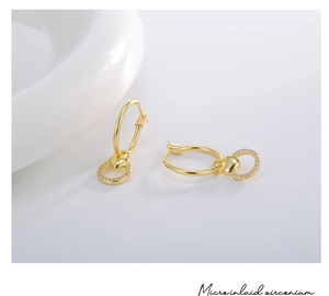 Close-up of golden heart earrings with micro-inlaid zirconium on a white surface
