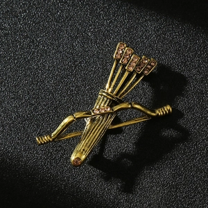 Macro shot of vintage golden bow and arrow brooch with inlaid colorful rhinestones