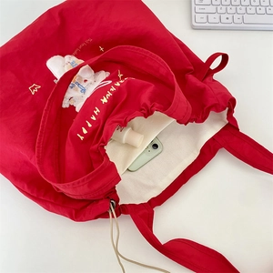 Macro view of red canvas tote bag interior with drawstring closure and rabbit embroidery