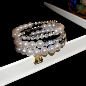 Détail d'un bracelet de perles multicouche avec diamants et un pendentif sac à main doré