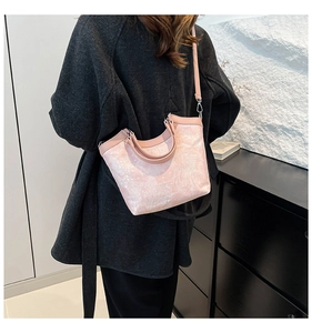 Detailed view of pink textured bucket bag worn with a dark coat for fashion contrast