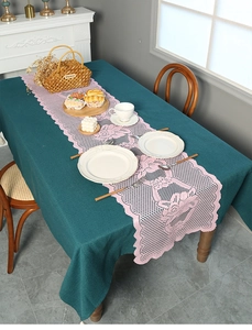 Detail of pink floral lace table runner with scalloped edges on linen cloth