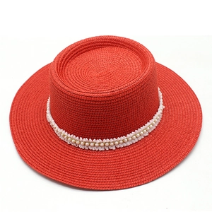 Detailed close-up of red straw boater hat featuring elegant white lace and pearl accents