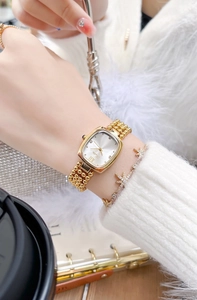 Lifestyle view of women's gold square watch with metal link strap on wrist