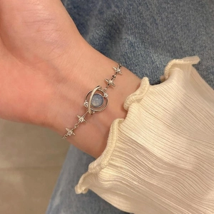 Detail of silver star bracelet with blue stone Saturn charm worn on wrist