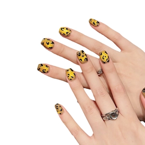Glossy yellow press-on nails with black leopard print pattern shown on female hand