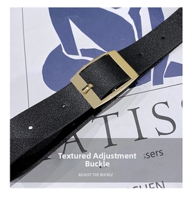 Detail of black pebbled leather belt with a polished gold rectangular buckle on a magazine