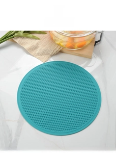 Close-up of teal round silicone honeycomb mat on marble table for heat protection