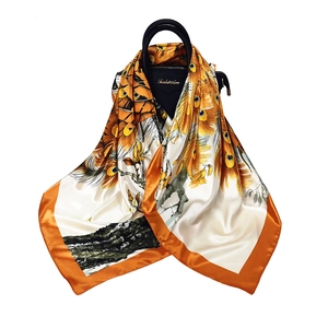 Peacock print silk-like square scarf in vibrant orange and beige on a handbag