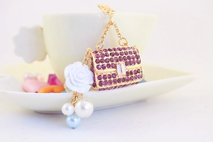 Detailed view of a purple rhinestone handbag keychain with white camellia and pearl beads