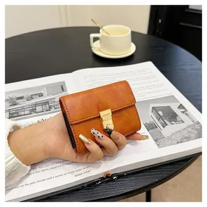 Detail of vintage caramel brown card holder with gold clasp held against lifestyle backdrop