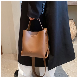 Close-up of caramel brown leather bucket bag with MACGHEE logo on minimalist design
