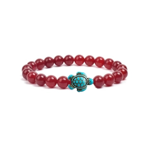 Detailed shot of red translucent stone bead bracelet with a turquoise turtle charm